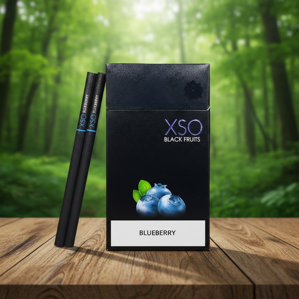 บุหรี่ XSO Blueberry กล่องสีดำลายพรีเมียม รูปผลบลูเบอร์รี่ วางคู่กับมวนบุหรี่สีดำบนโต๊ะไม้
