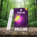 ซองบุหรี่ Oris Twin Sense Berry Mix สีม่วง พร้อมมวนบุหรี่ 2 มวน วางบนโต๊ะไม้ในสวนป่า