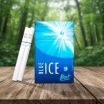 ซองบุหรี่ Blue Ice Blast สีน้ำเงินสว่างลายกราฟิกน้ำแข็ง วางบนโต๊ะไม้พร้อมมวนบุหรี่ในบรรยากาศป่าไม้