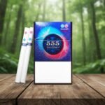 ซองบุหรี่ 555 State Express Sphere2 Velvety ดีไซน์สีน้ำเงินม่วง พร้อมมวนบุหรี่ก้นกรองแบบหลุม วางบนโต๊ะไม้ฉากหลังป่า