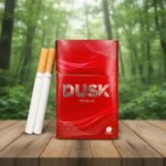 ซองบุหรี่ Dusk Premium สีแดงวางบนโต๊ะไม้ในบรรยากาศสวนป่าสีเขียว