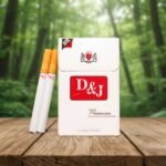 ซองบุหรี่ D&J Premium สีขาวแดงดีไซน์คลาสสิกวางบนโต๊ะไม้ฉากหลังป่าไม้ธรรมชาติ