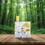 ซองบุหรี่ Zest Yogo Mango กลิ่นโยเกิร์ตมะม่วง พร้อมมวนบุหรี่ วางบนโต๊ะไม้ในบรรยากาศสวนป่าสีเขียว