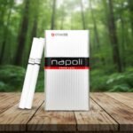 ซองบุหรี่ Napoli Silver สีขาวเงินสไตล์พรีเมียม วางบนโต๊ะไม้ฉากหลังเป็นป่าธรรมชาติ