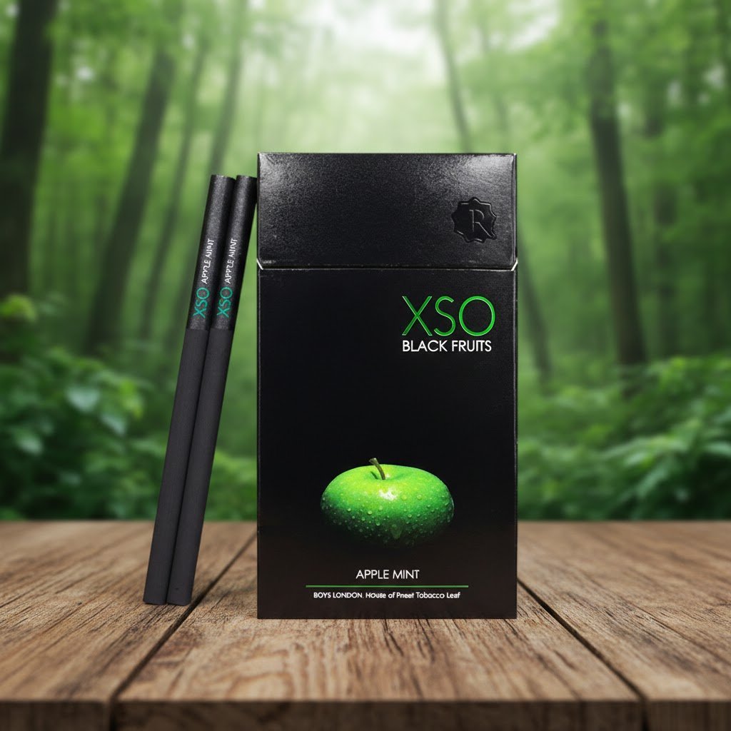 ซองบุหรี่ XSO Apple Mint สีดำพรีเมียม วางบนโต๊ะไม้ฉากหลังเป็นป่าสีเขียว