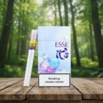 ซองบุหรี่ Esse Bubble Purple สีฟ้าขาวลายฟองสบู่สดใส วางคู่กับมวนบุหรี่สลิมบนโต๊ะไม้ ฉากหลังป่าไม้สีเขียว