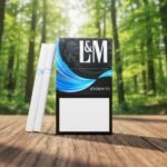 ซองบุหรี่ L&M Storm 7.1 สีดำลายคลื่นสีฟ้าสดใส วางบนโต๊ะไม้ฉากหลังป่าไม้ธรรมชาติ