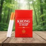 ซองบุหรี่กรองทิพย์ 90 ซองแข็งสีแดงคลาสสิก วางบนโต๊ะไม้ฉากหลังป่าไม้ธรรมชาติ