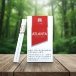 บุหรี่ Atlanta Red Super Slims ซองสีขาวแดงดีไซน์เรียบหรู วางบนโต๊ะไม้ฉากหลังป่าไม้ธรรมชาติ