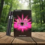 บุหรี่ Black Fox Raspberry ซองสีดำตัดสีชมพูฟูเชียพร้อมมวนบุหรี่สีดำล้วนวางบนโต๊ะไม้ฉากหลังป่า