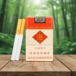 บุหรี่ Yuxi Softpack ซองอ่อนสีแดงสลับครีม ตราสัญลักษณ์จีนสีทอง พร้อมมวนบุหรี่ก้นกรองสีส้มวางบนโต๊ะไม้ฉากหลังป่า