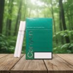 บุหรี่ Canyon Green ซองแข็งสีเขียวเข้ม ตัวอักษรสีทอง วางบนโต๊ะไม้ฉากหลังป่าธรรมชาติ