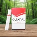 ซองบุหรี่ Carnival Red สีแดงสลับขาว วางบนโต๊ะไม้ท่ามกลางบรรยากาศป่าธรรมชาติ แสดงมวนบุหรี่สีขาวสองมวนด้านข้าง