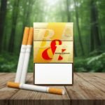 บุหรี่ Benson & Hedges ซองสีทองหรูหราพร้อมตราตั้งแห่งอังกฤษ วางบนโต๊ะไม้ฉากหลังป่าธรรมชาติ