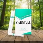 บุหรี่ Carnival Menthol ซองสีเขียวมินต์สลับขาว มวนบุหรี่สีขาวสะอาดก้นกรองแถบสีเขียว วางบนโต๊ะไม้ฉากหลังป่าธรรมชาติ