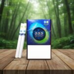 บุหรี่ 555 STATE EXPRESS Sphere2 Zesty ซองสีน้ำเงินลายตารางพรีเมียม แสดงมวนบุหรี่ 2 เม็ดบีบก้นกรองหลุม วางบนโต๊ะไม้ฉากหลังป่าสีเขียว