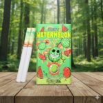 บุหรี่ Zest Watermelon ซองสีเขียวลายกราฟิกแตงโมพร้อมมวนบุหรี่เม็ดบีบ วางบนโต๊ะไม้ฉากหลังป่าสีเขียว