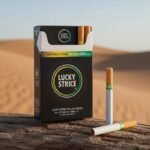 ซองบุหรี่ Lucky Strike Double Click Yellow-Green สีดำดีไซน์ทันสมัย วางบนขอนไม้ในทะเลทราย พร้อมมวนบุหรี่แสดงตำแหน่งเม็ดบีบ 2 จุด