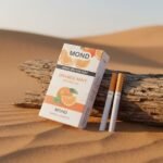 บุหรี่ Mond Orange Mint ซองสีขาวลายรูปส้มและใบมิ้นต์ วางพิงขอนไม้ในทะเลทราย พร้อมมวนบุหรี่ Superslims 2 มวน