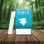 กล่องบุหรี่ Texas 5 Blue Menthol Ice สีฟ้าสดใส วางบนโต๊ะไม้ฉากหลังป่าไม้ธรรมชาติ